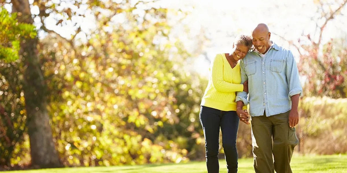 An older couple walking together outdoors, relaxed and unhurried.